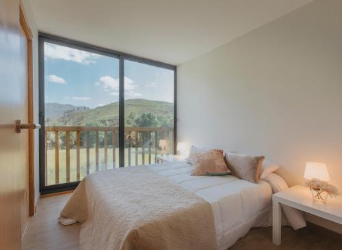 a bedroom with a bed and a large window at Casa Velha de Ponta Sôto in Cela