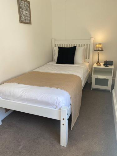 a bedroom with a white bed with a black pillow at The Tudor Hotel in Bridgwater