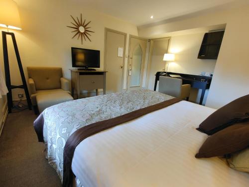 a hotel room with a large bed and a chair at The Priest House On The River in Castle Donington