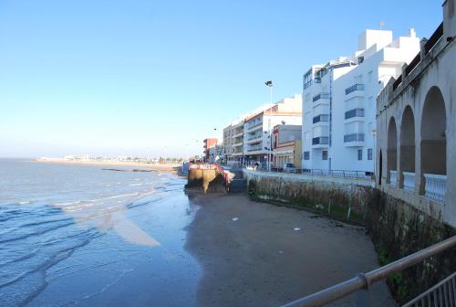 a beach with some buildings and the water and the ocean at Hostal Avenida by Bossh! Hotels in Chipiona