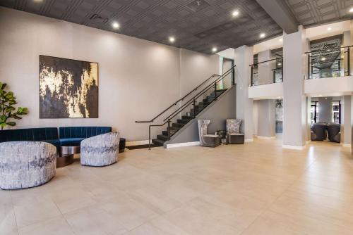 een lobby met een blauwe bank en stoelen en een trap bij Hourglass Hotel, Ascend Hotel Collection in Bakersfield