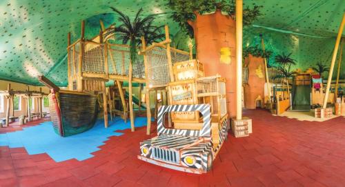 einen Spielplatz mit Rutsche in einem Gebäude mit Palmen in der Unterkunft Safariland Stukenbrock Erlebnisresort in Schloß Holte-Stukenbrock