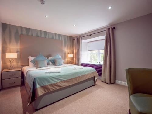 a bedroom with a bed with blue pillows and a window at Blackbull hotel in Tarbolton