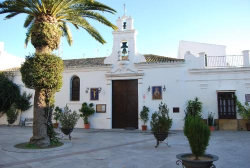 a church with a palm tree in front of it at Hostal Avenida by Bossh! Hotels in Chipiona