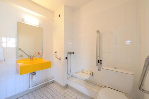 La salle de bains est pourvue d'un lavabo jaune et de toilettes. dans l'établissement Hôtel Kennedy Parc des Expositions, à Tarbes