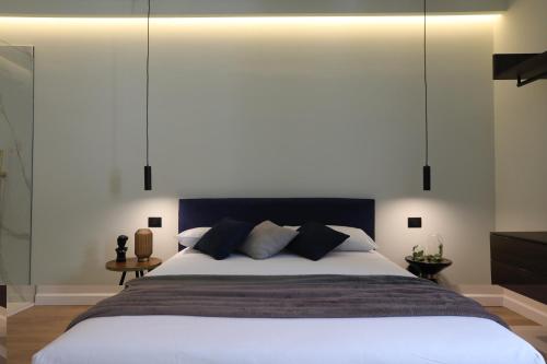 1 dormitorio con 1 cama blanca grande con almohadas negras en SCIABICA SUITE - Sicilian Experience, en Favara