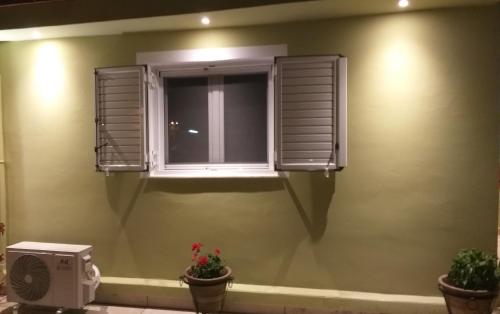 a window in a room with two potted plants at Vicky's place,near Athens airport in Koropíon