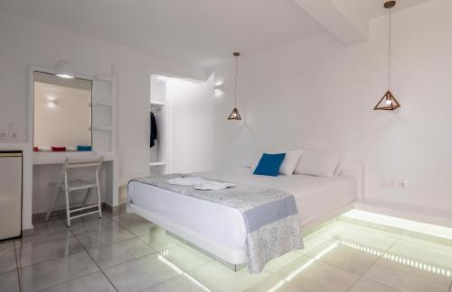 a white bedroom with a bed and a kitchen at Alexandros Village in Adamas