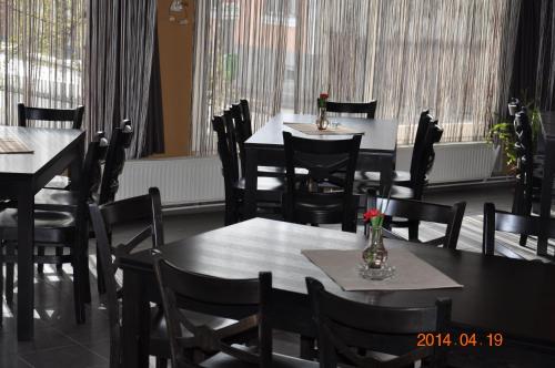 a dining room with tables and chairs and windows at Lázár Pension & Restaurant in Gheorgheni