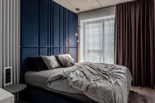 a bedroom with blue walls and a bed and a window at Urban center apartment in Vilnius