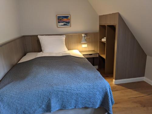 a bedroom with a bed with a blue blanket at Tetens Gasthof in Süderlügum