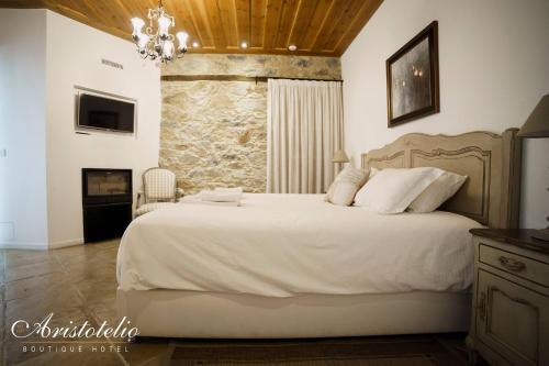 a bedroom with a large white bed with a fireplace at Aristotelio Boutique Hotel in Pedoulas