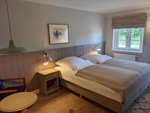 a bedroom with a bed and a table and a window at Tetens Gasthof in Süderlügum