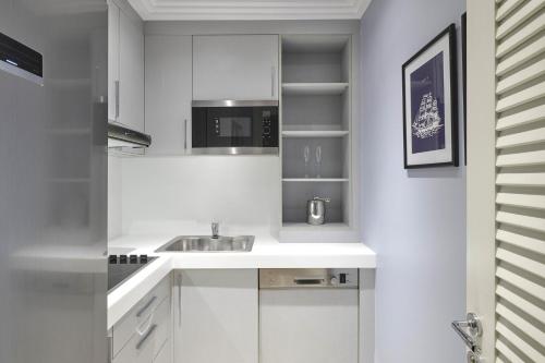 a white kitchen with a sink and a microwave at Four Seasons Hotel Alexandria At San Stefano in Alexandria