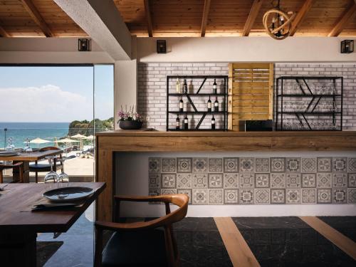 a dining room with a fireplace and a view of the ocean at Cavo Orient Beach Hotel & Suites in Tragaki
