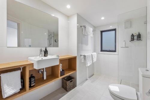 a white bathroom with a sink and a toilet at Benny's Retreat Luxury Bushland Escape in Clare