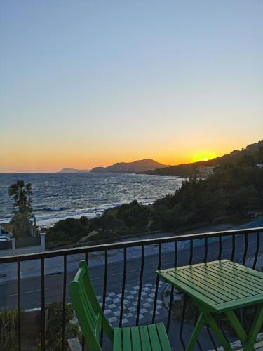 a table and chairs on a balcony with the sunset at Hôtel Almanarre Plage - Hôtel Eco-Responsable face à la mer in Hyères