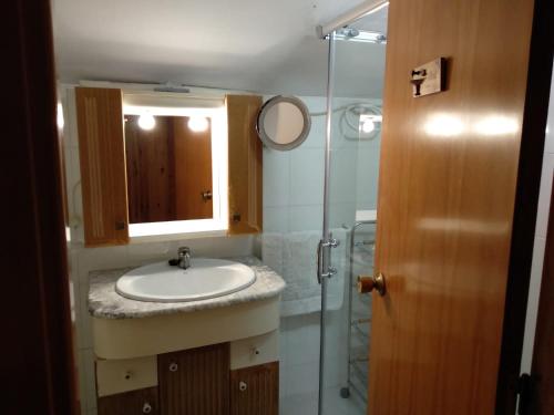 ein Bad mit einem Waschbecken und einer Glasdusche in der Unterkunft Apartamento dúplex acogedor con piscina en Rialp in Rialp
