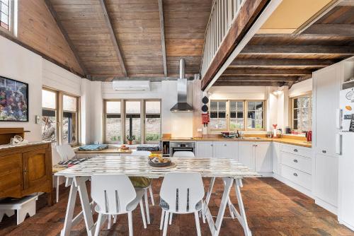 a kitchen with a table and white chairs at Benny's Retreat Luxury Bushland Escape in Clare