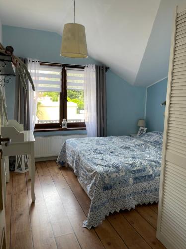 a blue bedroom with a bed and a window at Dom w centrum Dziwnowa in Dziwnów