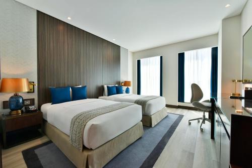 two beds in a hotel room with blue pillows at Bahrain Airport Hotel Airside Hotel for Transiting and Departing Passengers only in Muharraq