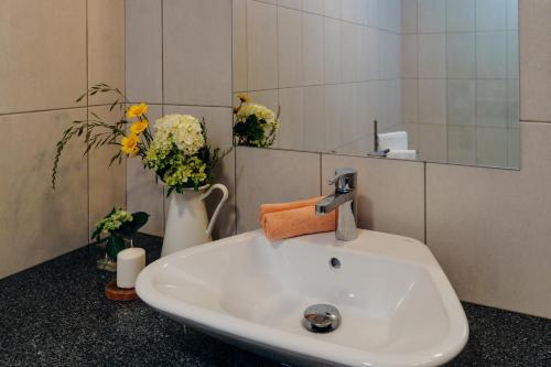 baño con lavabo, espejo y flores en Casa da Ribeira do Além, en Angra do Heroísmo