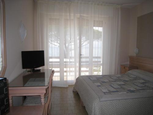 een slaapkamer met een bed en een bureau met een computer bij Hotel Esperia in Lazise