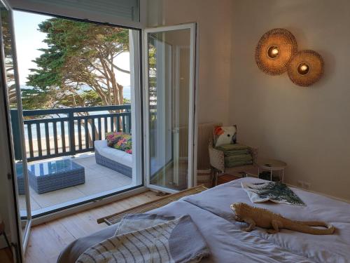 ラ・ボールにあるLes Cigalesのバルコニー付きの寝室のベッドに横たわる猫