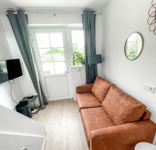 sala de estar con sofá marrón y ventana en Gastenverblijf De Ruyter, en Koudekerke