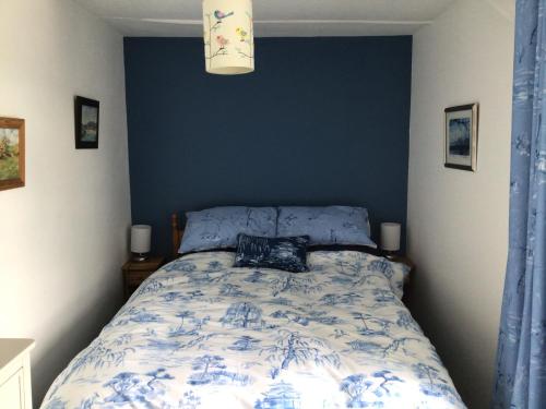 a bedroom with a bed with a blue wall at Victoria Cottage in Reeth