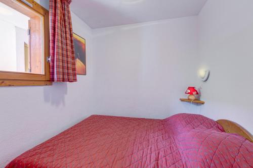 a bedroom with a bed with a red comforter and a window at Les Valmonts 403 in Les Menuires