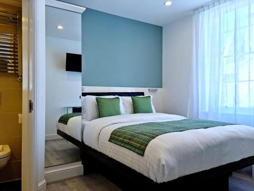 a bedroom with a large bed with green pillows at 146 STUDIOS Regent's Park in London