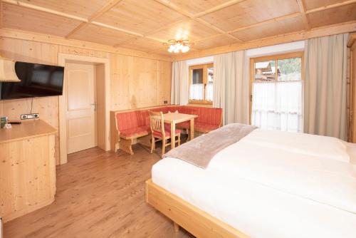 a bedroom with a bed and a table and a kitchen at Das kleine, feine SONNWEND in Alpbach