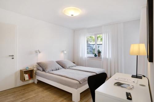 a white bedroom with a bed and a window at Ferienwohnung Silvia in Weißensberg