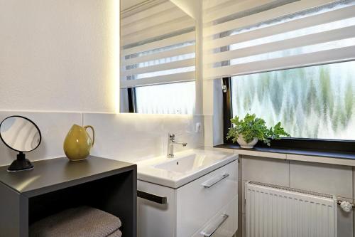 a bathroom with a sink and a window with a mirror at Ferienwohnung Silvia in Weißensberg