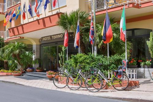 a row of bikes parked in front of a building with flags at Hotel Torino Wellness & Spa in Diano Marina