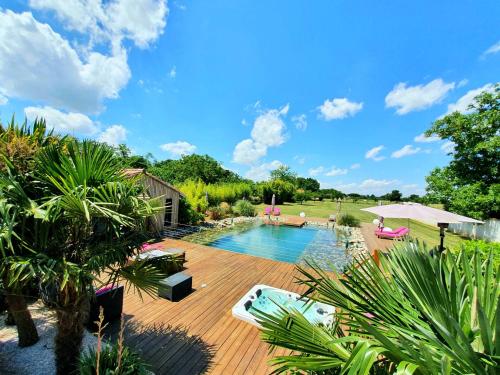 a backyard with a swimming pool and a wooden deck at Les Granges de Jules in Lafitte-Vigordanne