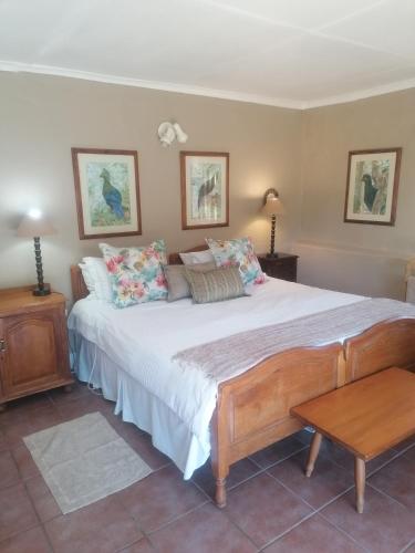 a bedroom with a large bed and a table at Hornbills Forest Cottages in Stutterheim