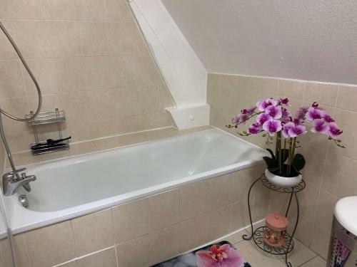 baño con bañera blanca con flores púrpuras en La Visitation - 30 en Orthez