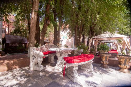 a table and two benches with red pillows on it at Amsterdam Hotel Aktobe in Aktobe
