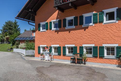 an orange and green building with green shuttered windows at Fewo im Gästehaus Maximilian in Eggelsberg