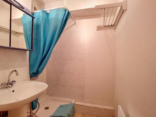 La salle de bains est pourvue d'un lavabo et d'une douche avec un rideau bleu. dans l'établissement Ourson 14, à Saint-Jean-dʼAulps
