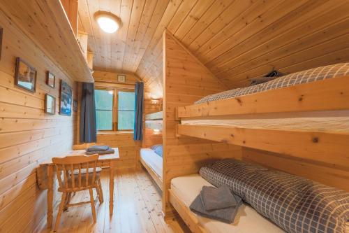a log cabin bedroom with two bunk beds and a desk at Guesthouse / Huskyfarm Innset in Innset