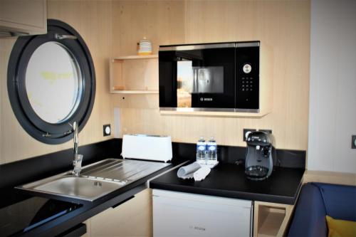 a small kitchen with a sink and a microwave at Les Ilots de Gruissan in Gruissan