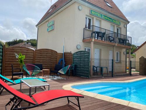 een patio met een zwembad en stoelen en een gebouw bij Dday House in Saint-Laurent-sur-Mer