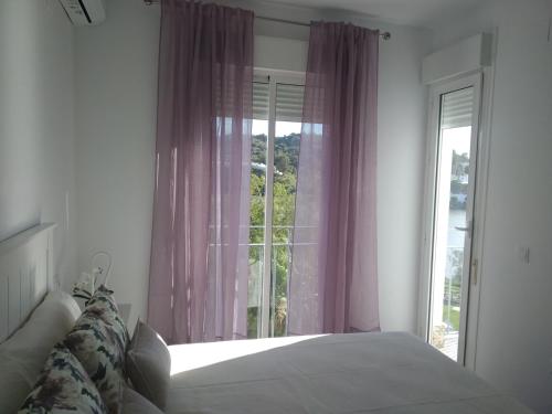 a bedroom with a bed and a window with pink curtains at La Carbonera in Sanlúcar de Guadiana