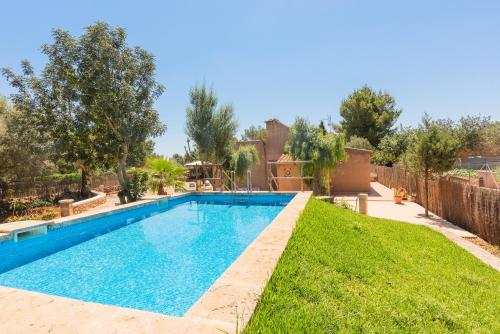a swimming pool in a yard with grass and trees at Villa Es Tres Pins in Campos