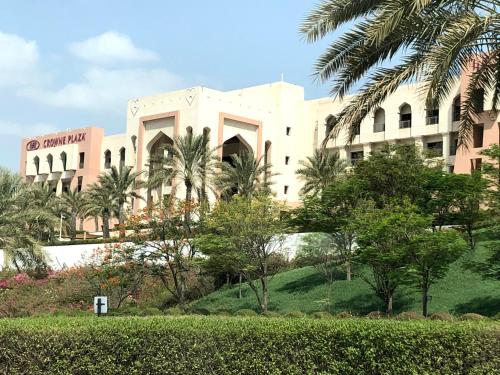a building with palm trees in front of it at Crowne Plaza Sohar by IHG in Sohar