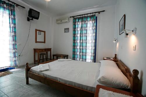a bedroom with a large bed and two windows at Oasis Azolimnos in Azolimnos Syros