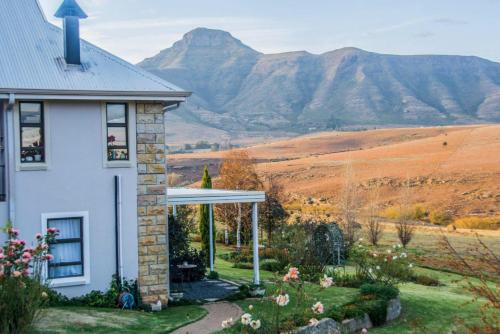 a white house with a view of a mountain at Jovali Clarens in Clarens